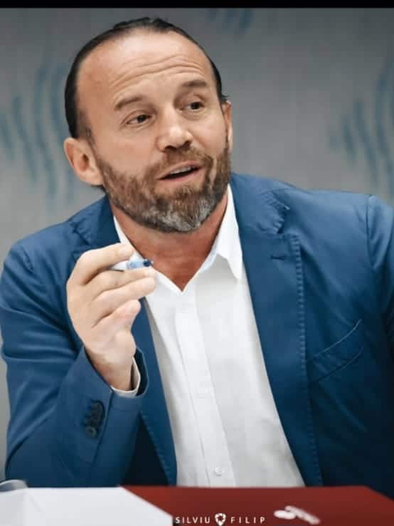 Bărbat vorbind la o întâlnire, ținând un stilou